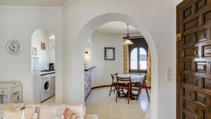 Una cocina con lavadora, una zona de comedor con mesa y sillas, y una puerta de madera.