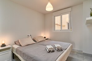 Une chambre à coucher avec un lit, des lampes de chevet, une fenêtre et une étagère fixée au mur.