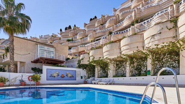 A swimming pool with a metal ladder, lounge chairs, and a mural of sea creatures.
