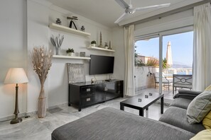 Un salon moderne doté d’un téléviseur à écran plat, d’un canapé, d’une table basse et d’un coin repas avec une table et des chaises.