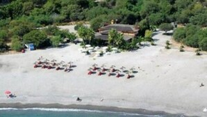 An aerial view of a beach with a building and several umbrellas.