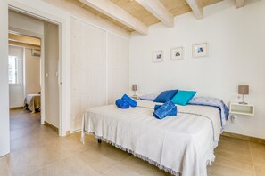 Une chambre à coucher avec un lit, des oreillers, une table de chevet et une lampe fixée au mur.