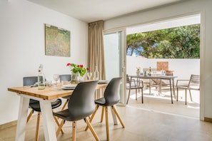 Un coin repas avec une table dressée pour quatre personnes, des chaises, un vase rempli de fleurs et un tableau accroché au mur.