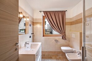 Une salle de bain avec deux lavabos, des toilettes et une douche.