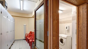 Ein öffentliches WC mit Schließfächern, einer Waschmaschine und roten Stühlen.