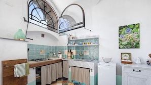A compact kitchen with a tiled backsplash, a window with an arch, and a small refrigerator. - 'Lavanda' Apartment with Sea View, Garden, and Wi-Fi (Finale Ligure)