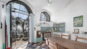 A kitchen with a dining area, a large window, and a tiled floor. - 'Lavanda' Apartment with Sea View, Garden, and Wi-Fi (Finale Ligure)
