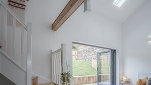 Ein modernes Interieur mit Treppe, Pflanze und Blick auf einen Garten durch eine Glastür.