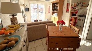 A compact kitchen with a dining area, a sofa, and a table with a vase of flowers. - Bright city-center apartment for 4 people (Arcachon)