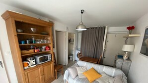 A bedroom with a bed, a wooden wardrobe, a dining table, a lamp, and a bathroom in the background. - Bright city-center apartment for 4 people (Arcachon)