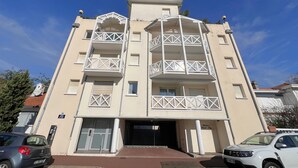 A multi-story building with balconies, a gated entrance, and a parking area. - Bright city-center apartment for 4 people (Arcachon)