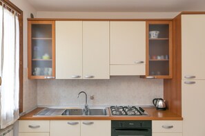 Une cuisine équipée d’un évier, d’une cuisinière et de placards.