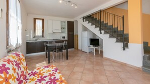 A modern apartment with a kitchen, dining area, and a staircase. - Apartment 'Bilocale Correggiolo' with Terrace, Shared Pool & Wi-Fi (Suvereto)