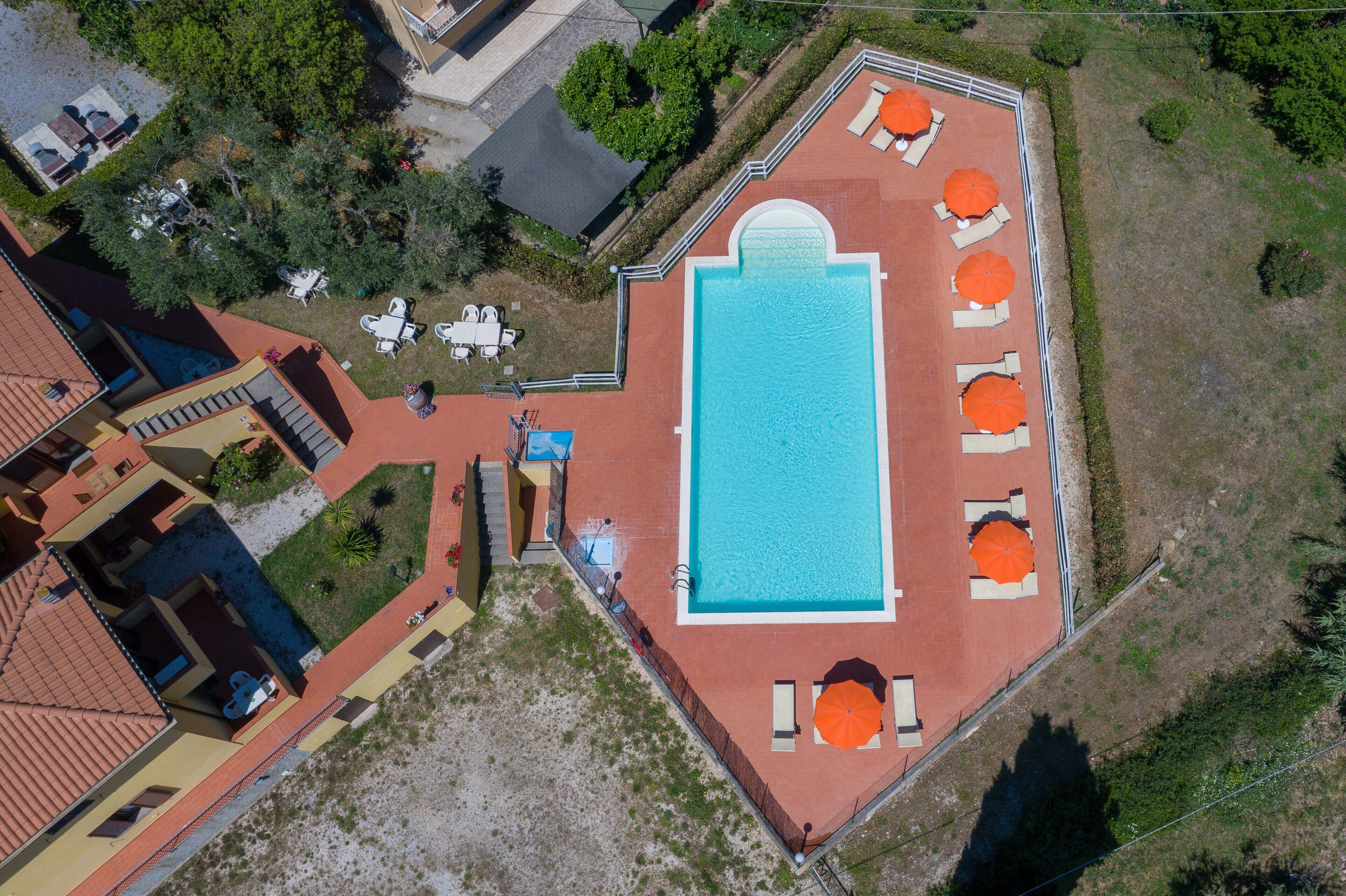 Vue aérienne d’une propriété dotée d’une piscine, d’un espace salon extérieur et d’un jardin aménagé.