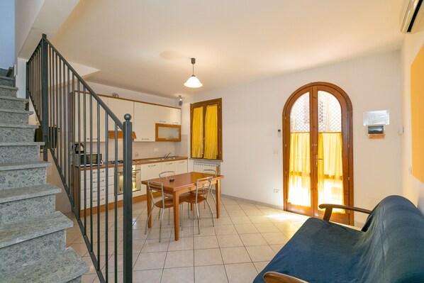 Un escalier menant à une cuisine équipée d’une table et de chaises, d’un canapé et d’une grande fenêtre en arc de cercle.