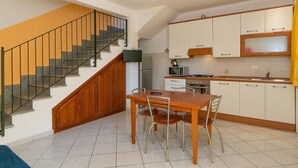 Una cucina con tavolo da pranzo, sedie, una scala e pensili.
