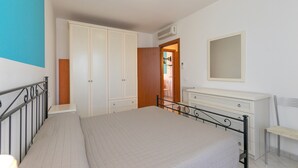 A bedroom with a bed, wardrobe, dresser, and a mirror. - Apartment 'Bilocale Ansonica' with Balcony, Shared Pool & Wi-Fi (Suvereto)