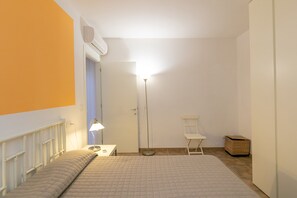 A bedroom with a bed, bedside table, lamp, and a standing floor lamp.