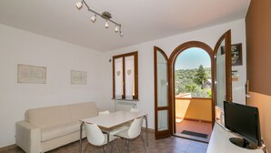 Une pièce comprenant un canapé, une table à manger, des chaises, un téléviseur et un balcon avec vue.