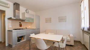 Une cuisine compacte avec un coin repas, un canapé et une horloge au mur.