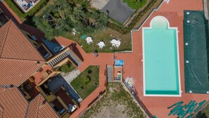 An aerial view of a hotel with a swimming pool, outdoor seating, and a covered patio area.