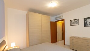 A bedroom with a bed, a dresser, a wardrobe, and a door leading to another room.