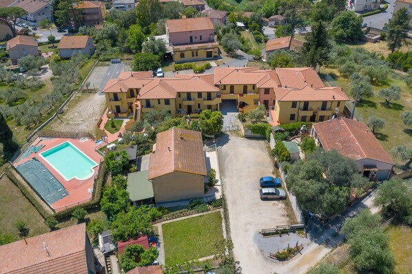 Vue aérienne d’un quartier résidentiel comprenant plusieurs maisons à deux étages, une piscine et un espace de stationnement.