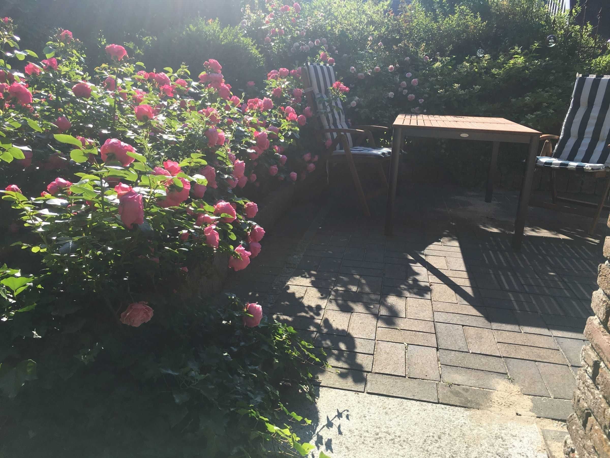 A patio area with a stone floor, two striped chairs, and a table.