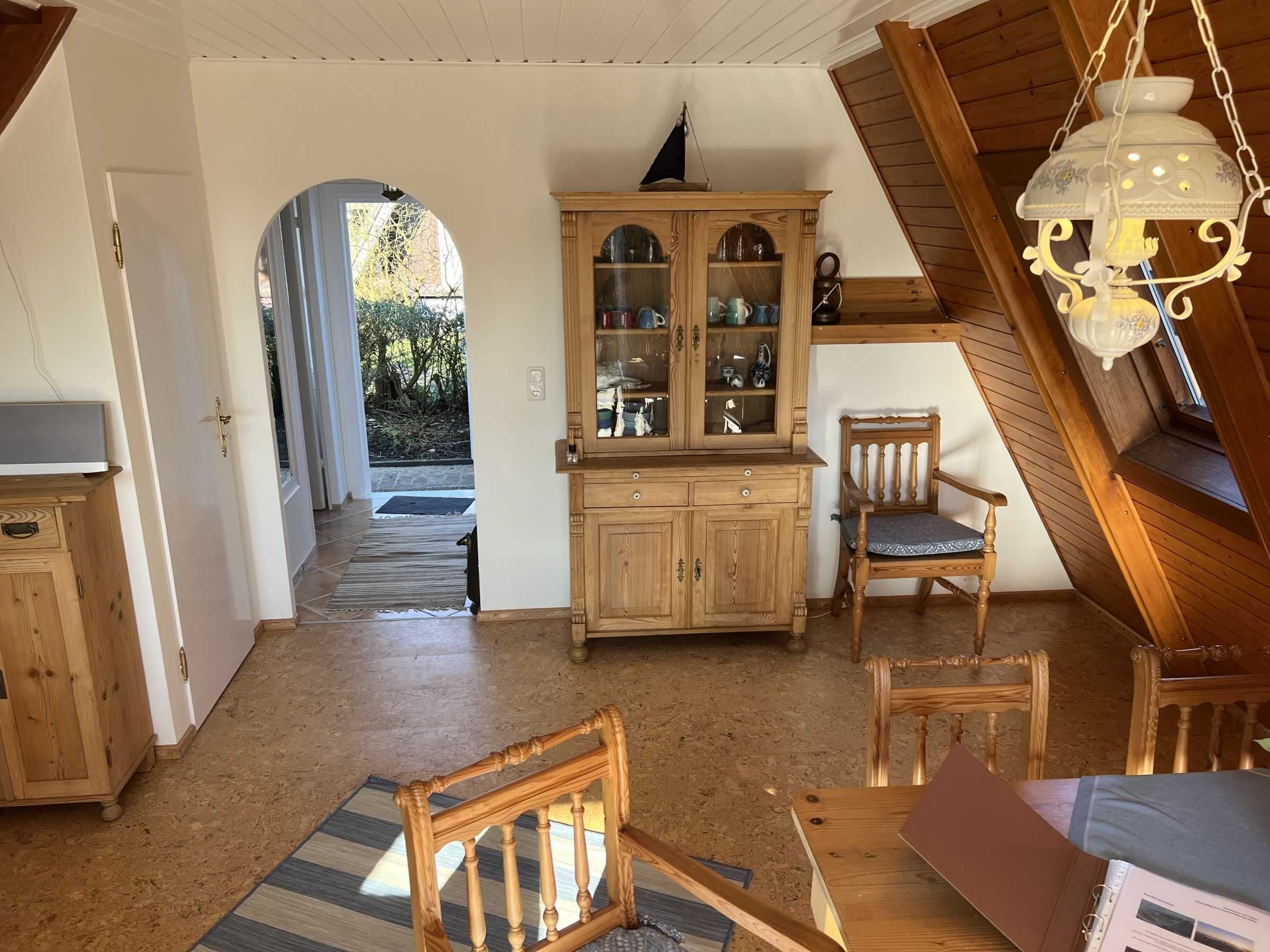 Ein gemütliches Zimmer im Dachgeschoss mit einem Holzschrank, einem Sessel und einem Schreibtisch.