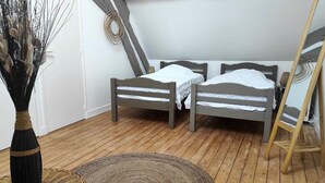 A room with two wooden beds, a woven rug, and a tall vase with dried plants. - Charming Riverside Cottage with Private Grounds, Fishing, Pet-Friendly, WiFi, and Parking (Mareuil-sur-Arnon)