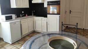 A compact kitchen with white cabinets, a microwave, a coffee maker, and a stove. - Charming Riverside Cottage with Private Grounds, Fishing, Pet-Friendly, WiFi, and Parking (Mareuil-sur-Arnon)