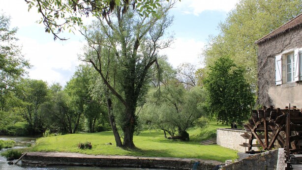 A historic building with a water wheel, surrounded by lush greenery and a calm river. - Charming Riverside Cottage with Private Grounds, Fishing, Pet-Friendly, WiFi, and Parking (Mareuil-sur-Arnon)