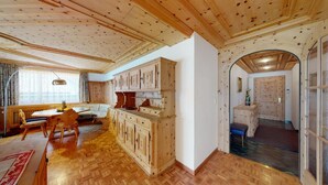 A wooden interior with a dining area, kitchen, and an arched doorway leading to another room. - In the heart of St. (St. Moritz)