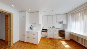 A modern kitchen with white cabinetry, a built-in oven, and a herringbone-patterned wooden floor. - In the heart of St. (St. Moritz)