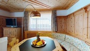 A wooden cabin interior with a dining table, a bench, a television, and a window with curtains. - In the heart of St. (St. Moritz)