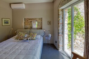 A bedroom with a bed, a nightstand, a lamp, a window with a view of greenery, and an air conditioning unit. - Villa with heated pool and amazing view, Camaiore (Camaiore)