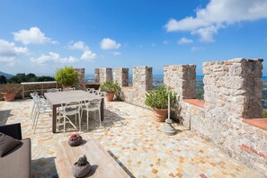 A terrace with a table and chairs, potted plants, and stone walls overlooking a coastal view. - Villa with heated pool and amazing view, Camaiore (Camaiore)