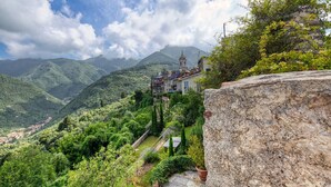 A mountain village with a prominent church on a hill, surrounded by lush greenery and a stone wall. - Villa with heated pool and amazing view, Camaiore (Camaiore)