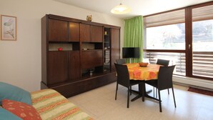 A dining area with a table, chairs, a cabinet, and a window with blinds.
