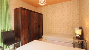 A bedroom with a bed, a chair, a wardrobe, and a bedside table with a lamp.
