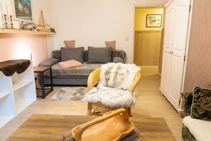A living room with a sofa, a chair, a wooden coffee table, and a white cabinet.