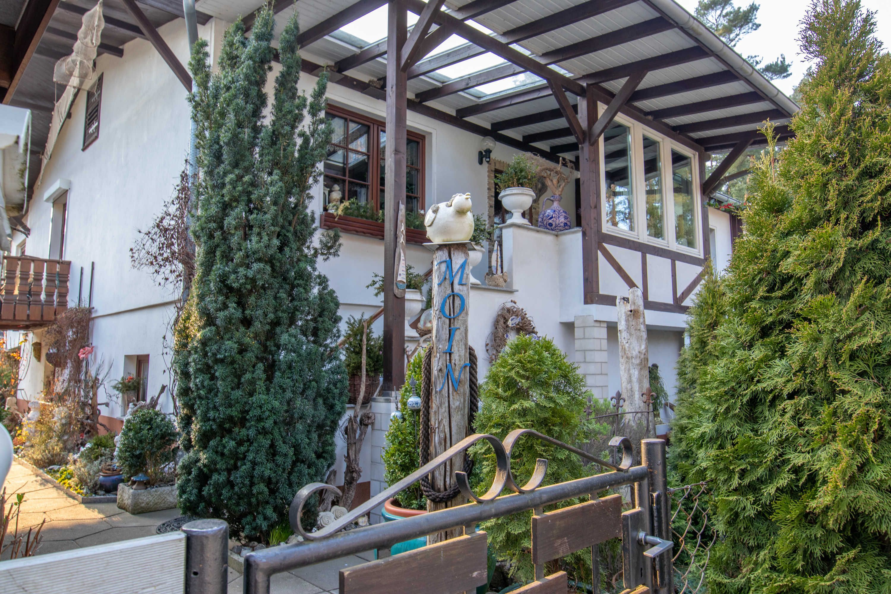Een traditioneel chalet met een houten balkon, een overdekte veranda en verschillende plantenbakken.