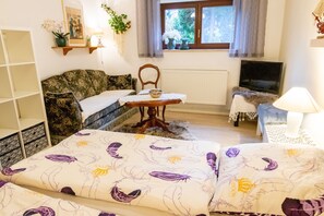 A cozy room with a bed, a sofa, a small table, a TV, and a window with curtains. - Vacation apartment Timmy - Holiday apartment (Lubmin)