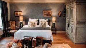 A bedroom with a large bed, two bedside lamps, a chair, a cabinet, and two framed pictures on the wall. - Maison Mairie (Hasselt)