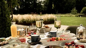 An outdoor dining setup with a table set for a meal, including plates, glasses, and a variety of food items. - Maison Mairie (Hasselt)