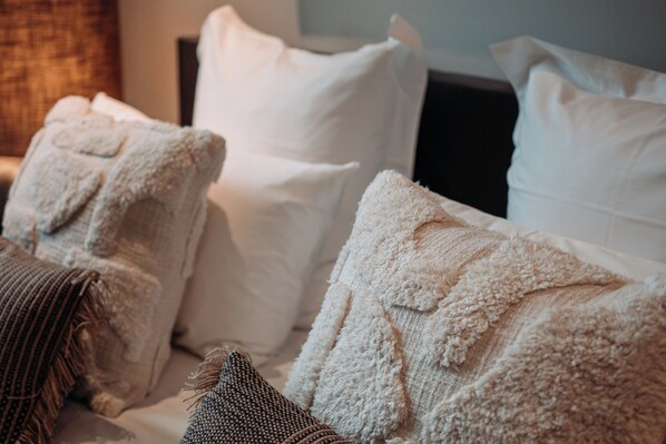 A bed with white pillows and a textured blanket.