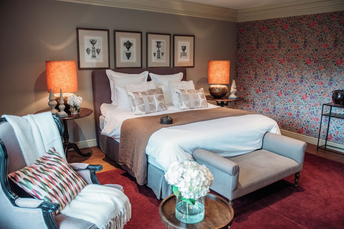 A well-appointed bedroom with a large bed, two bedside tables, a chair, and a sofa.