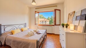 A bedroom with a bed, a window, a dresser, and a view of buildings outside. - Residenza Il Parco - Family Retreat With Garden (Ispra)