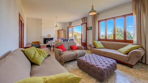 A spacious living area with a sofa, ottoman, and dining table. - Residenza Il Parco - Family Retreat With Garden (Ispra)