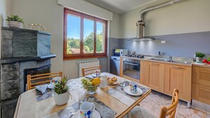 A modern kitchen with a dining area, a built-in stove, and a window with a view. - Residenza Il Parco - Family Retreat With Garden (Ispra)